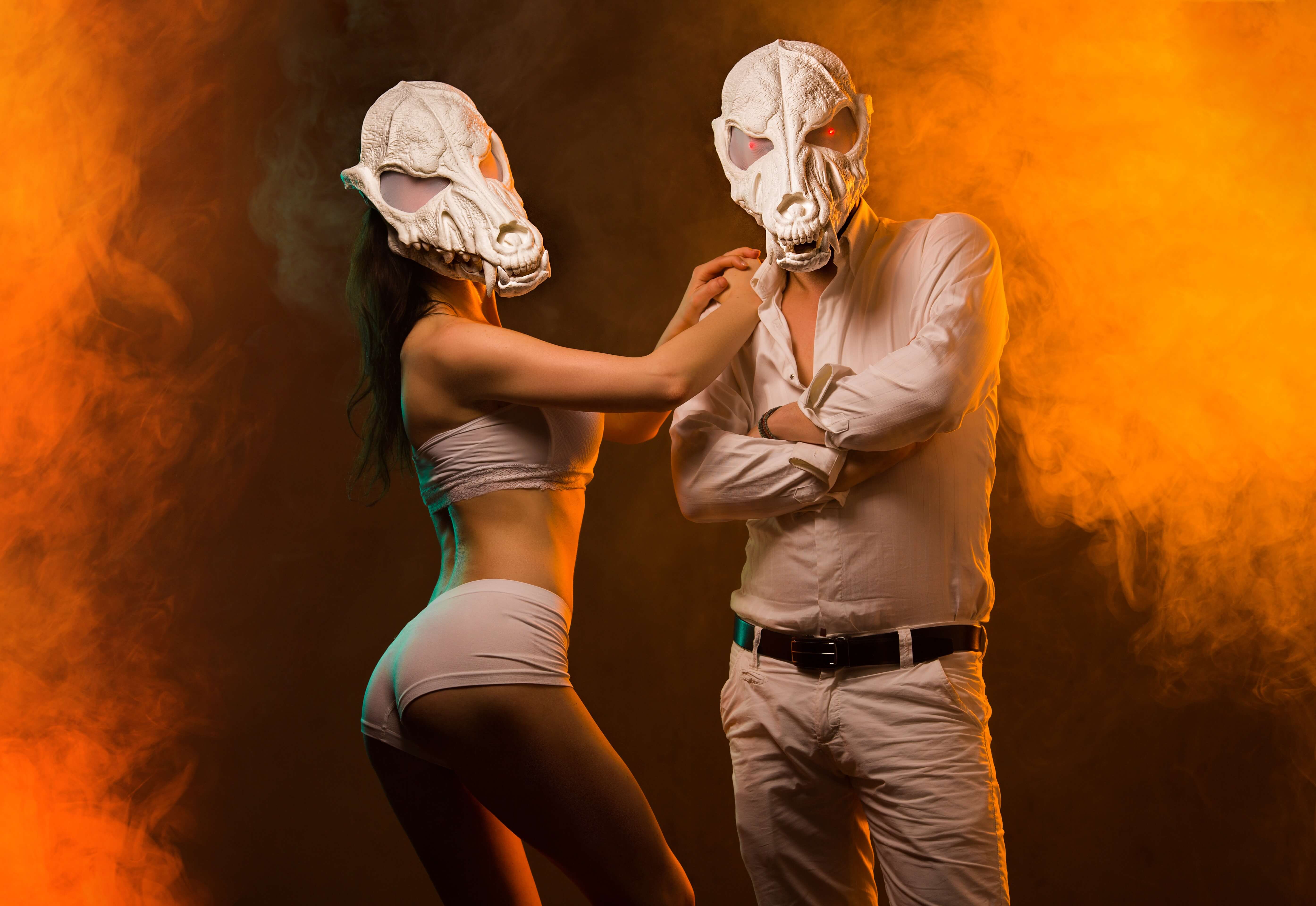 White wolf skull masks worn by couple - dramatic orange smoke background